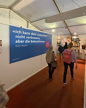Menschen gehen in einen Ausstellungsraum mit einer blauen Informationstafel