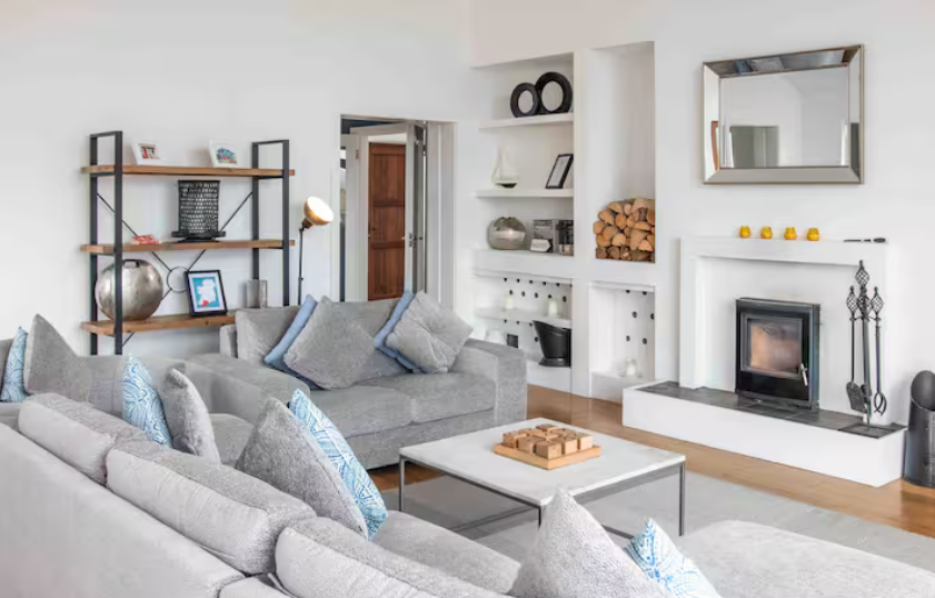 A bright, open living space with sweeping views, a warming fire, and shelves of books and games for slow, relaxed evenings.