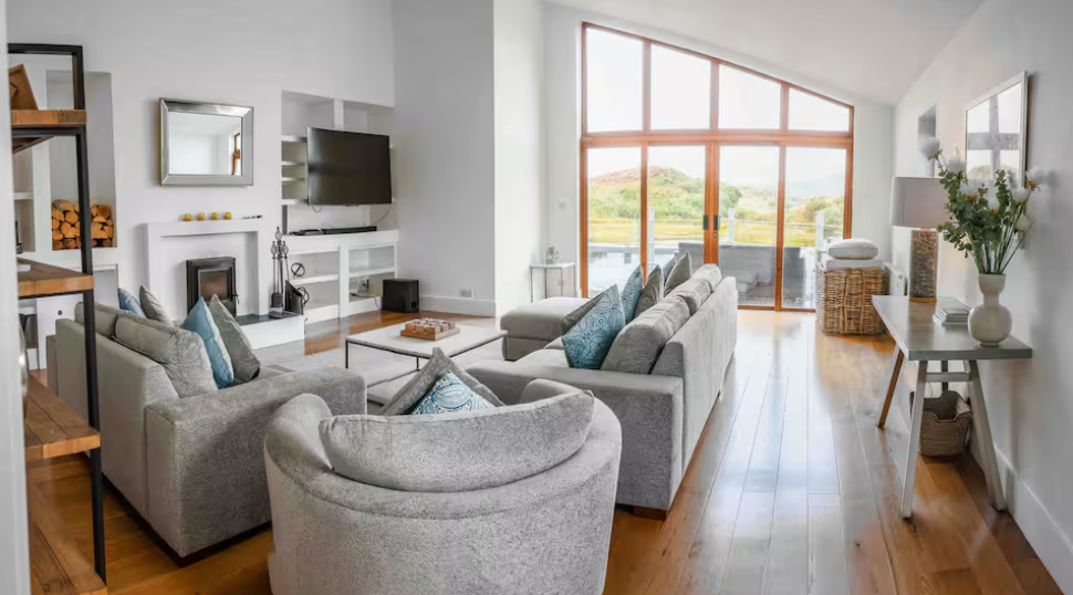 The Living Space - A bright, open living area with sweeping views, a warming fire, and shelves of books and games for slow, relaxed evenings.