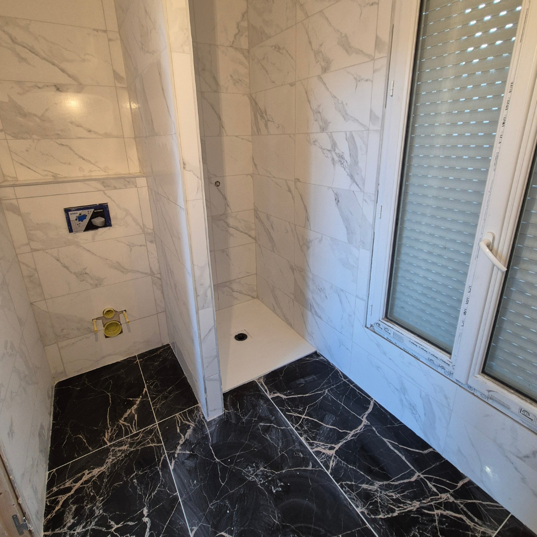 Salle de douche avec murs en marbre blanc et sol en marbre noir avec veines blanches, fenêtre avec volets roulants
