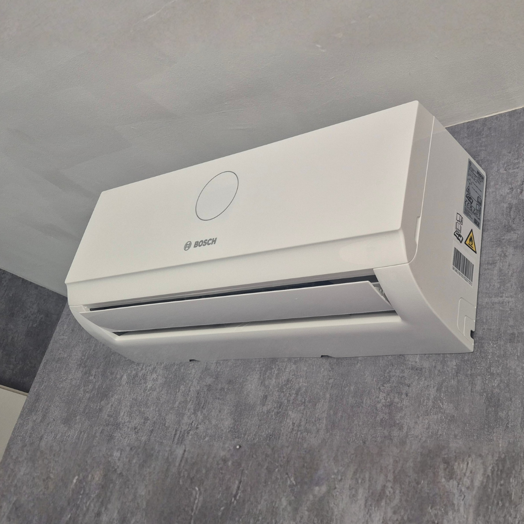 Climatiseur blanc mural de la marque Bosch installé sur un mur en carrelage gris
