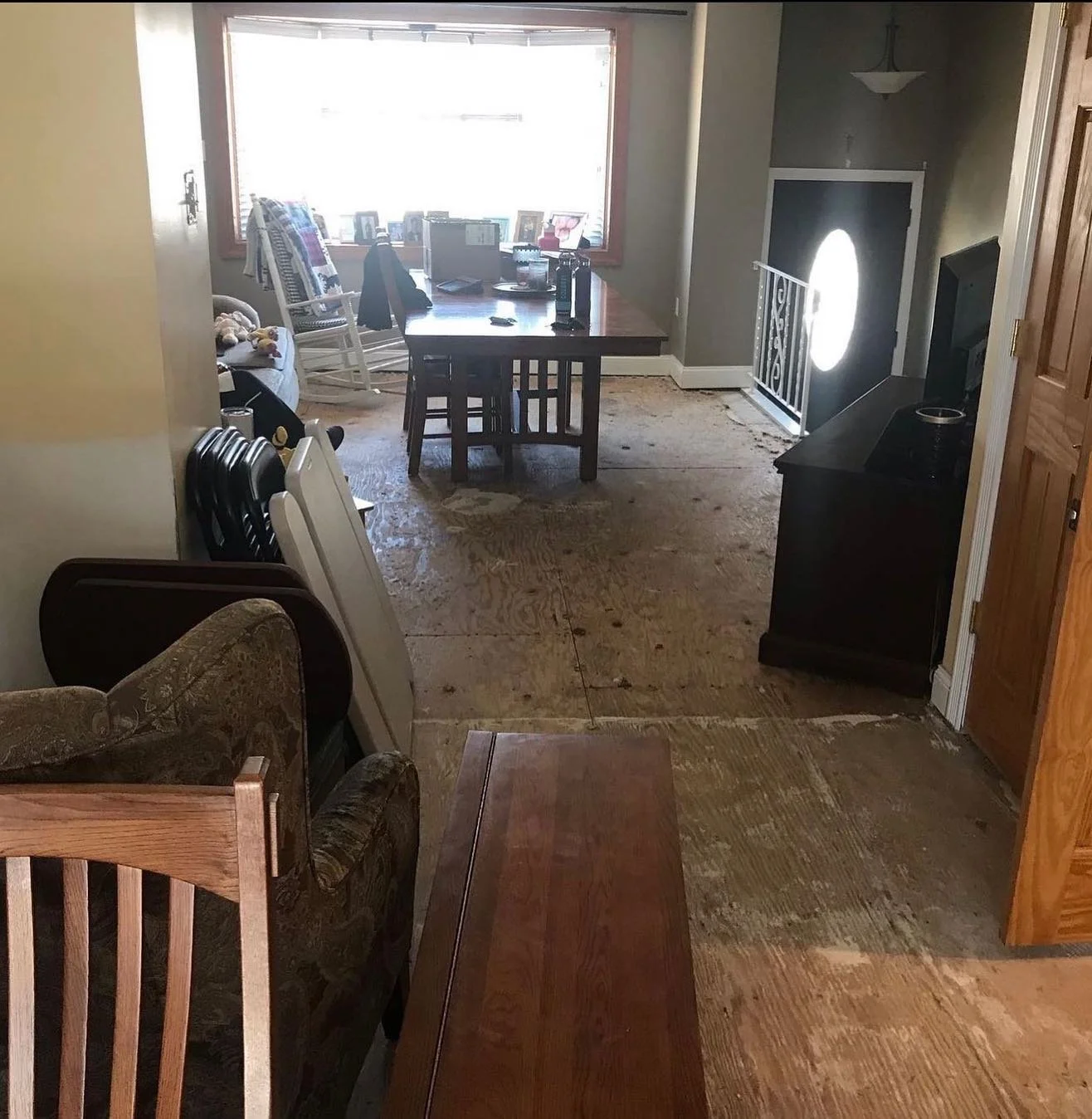 Living and dining area with old flooring removed to expose the plywood subfloor.