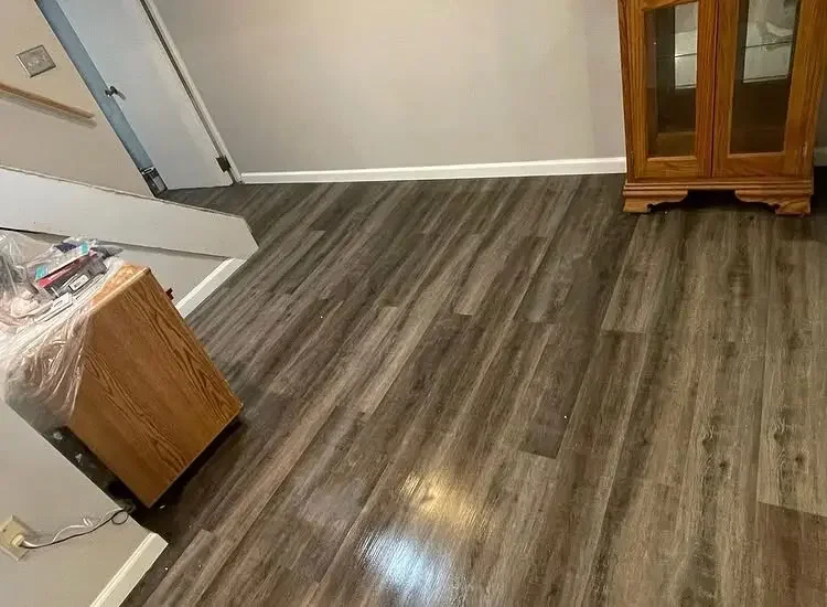 Gray luxury vinyl plank flooring installed through a Bucks County living area with white baseboards.