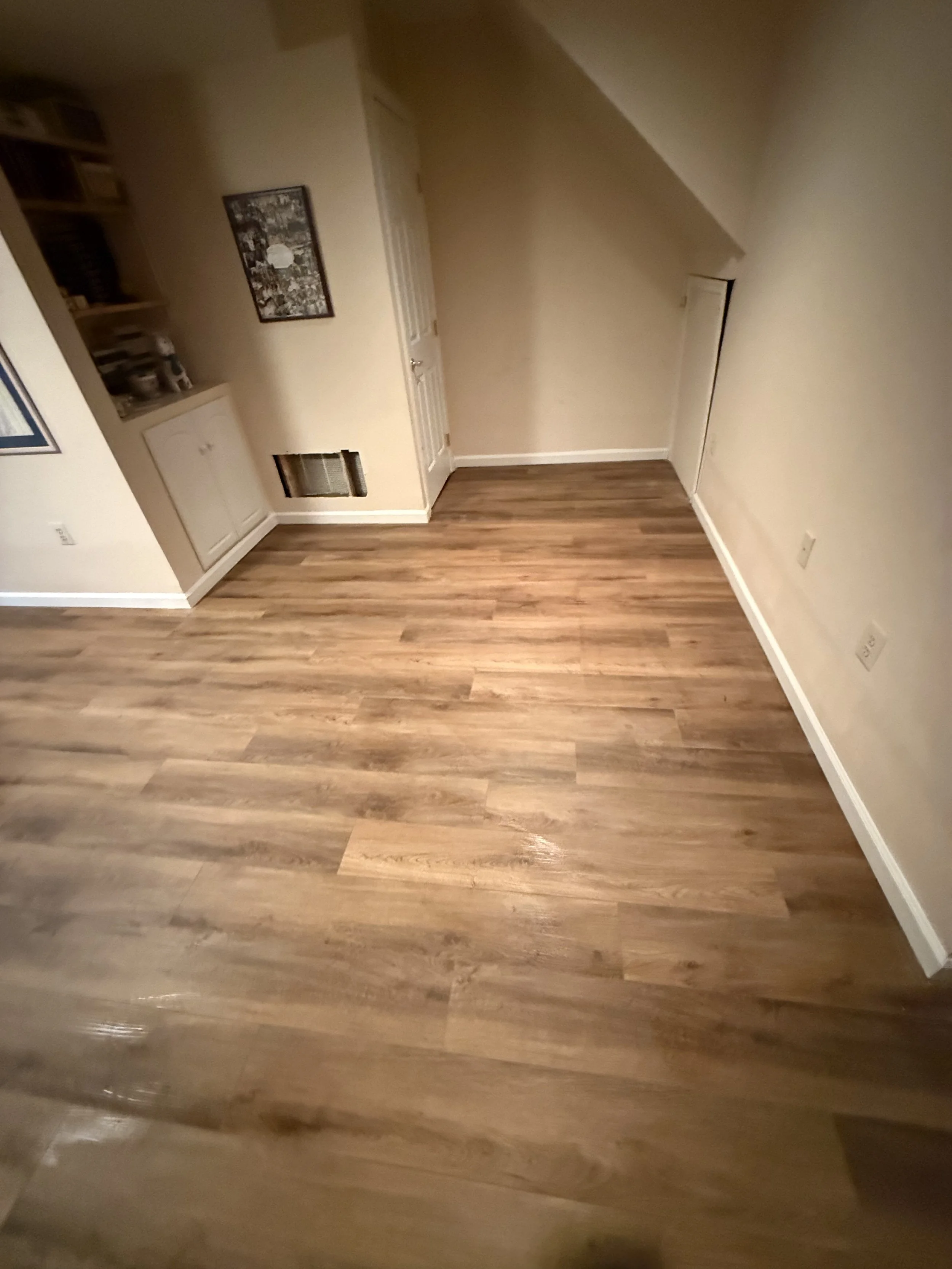 Finished warm brown wood-look plank flooring extending across an open living area.