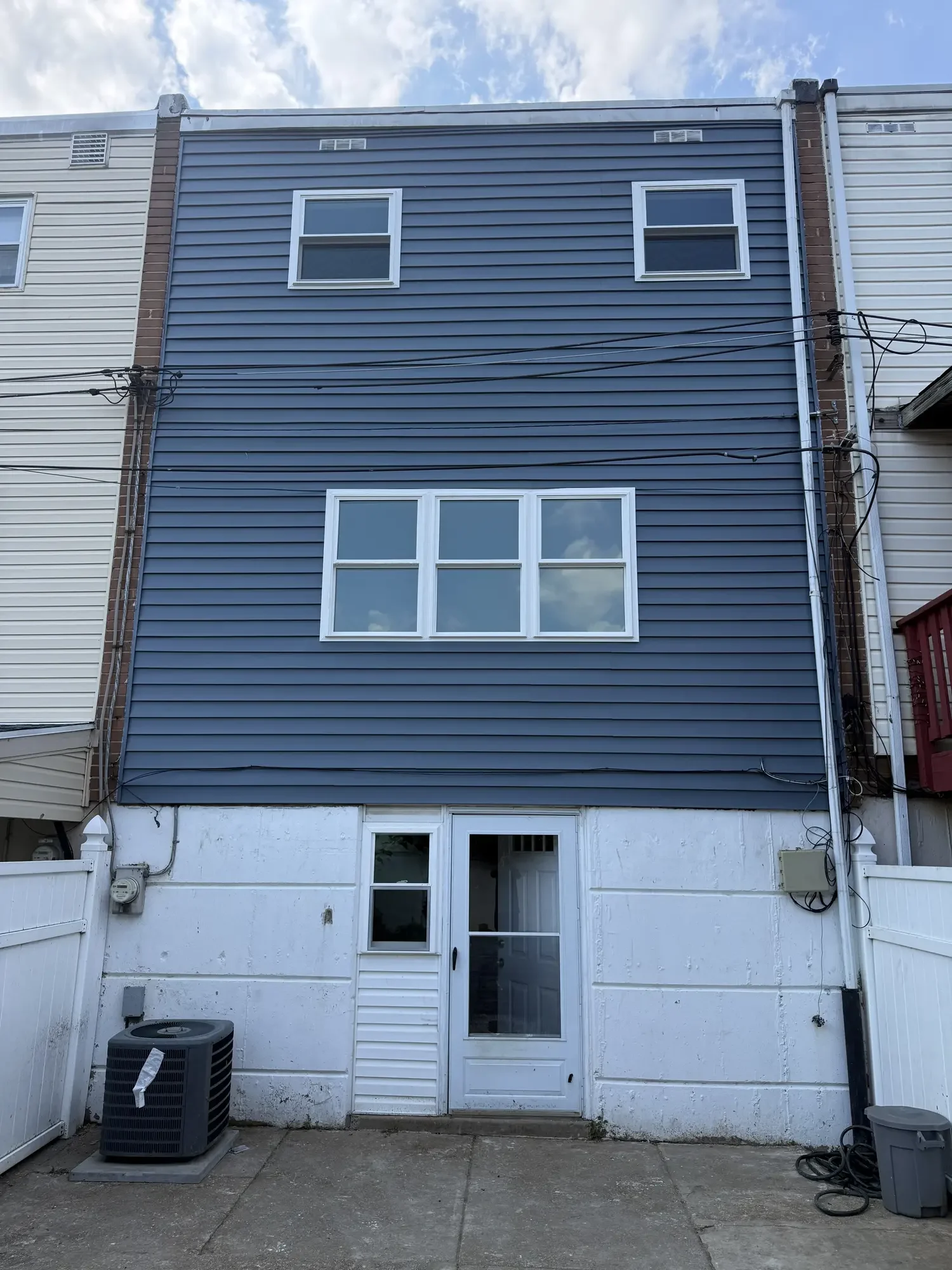 Completed blue vinyl siding and replacement-window exterior renovation on a Bucks County rowhome.