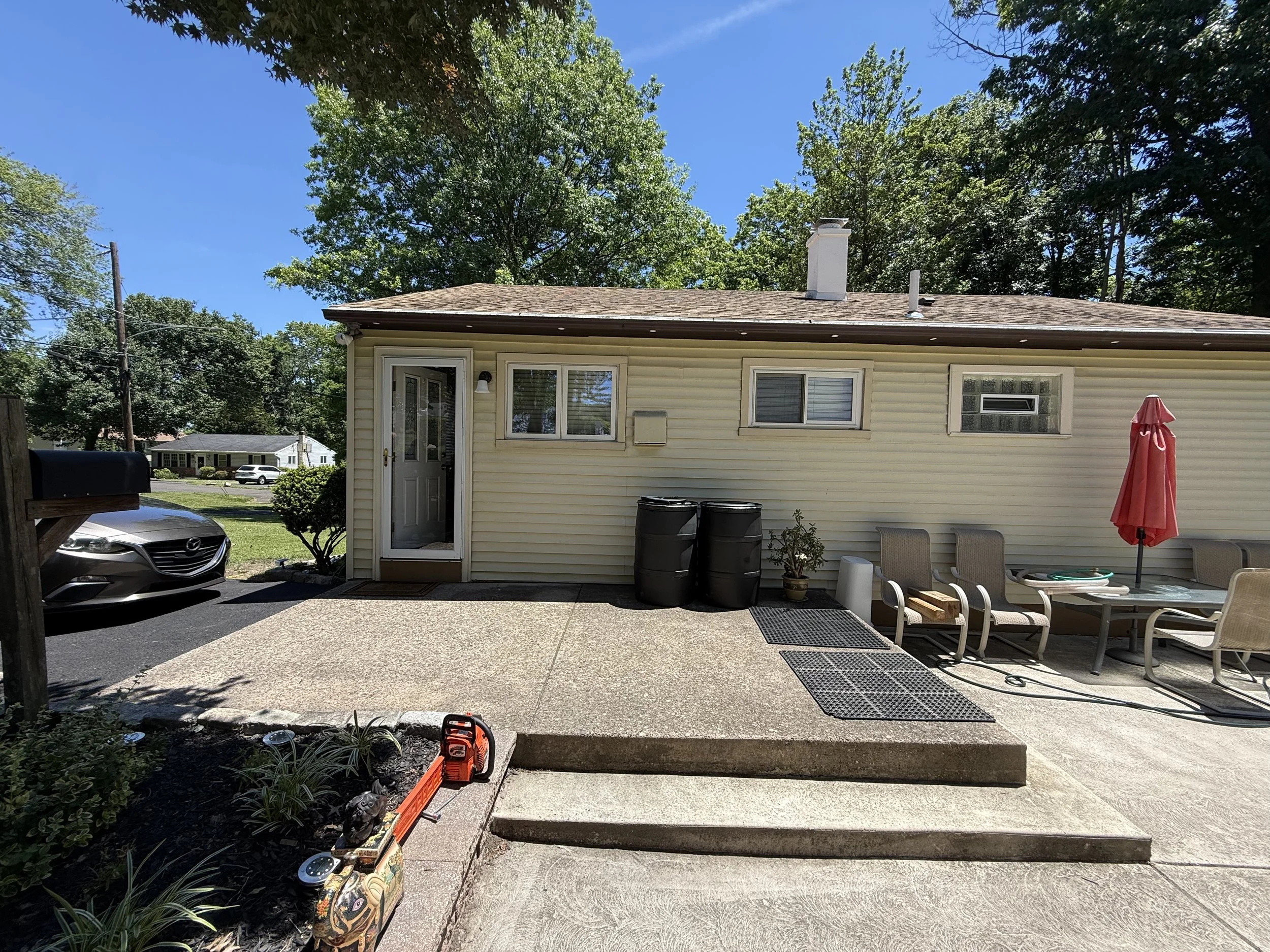 Rear exterior with light siding, windows, a back door, concrete patio, and steps.