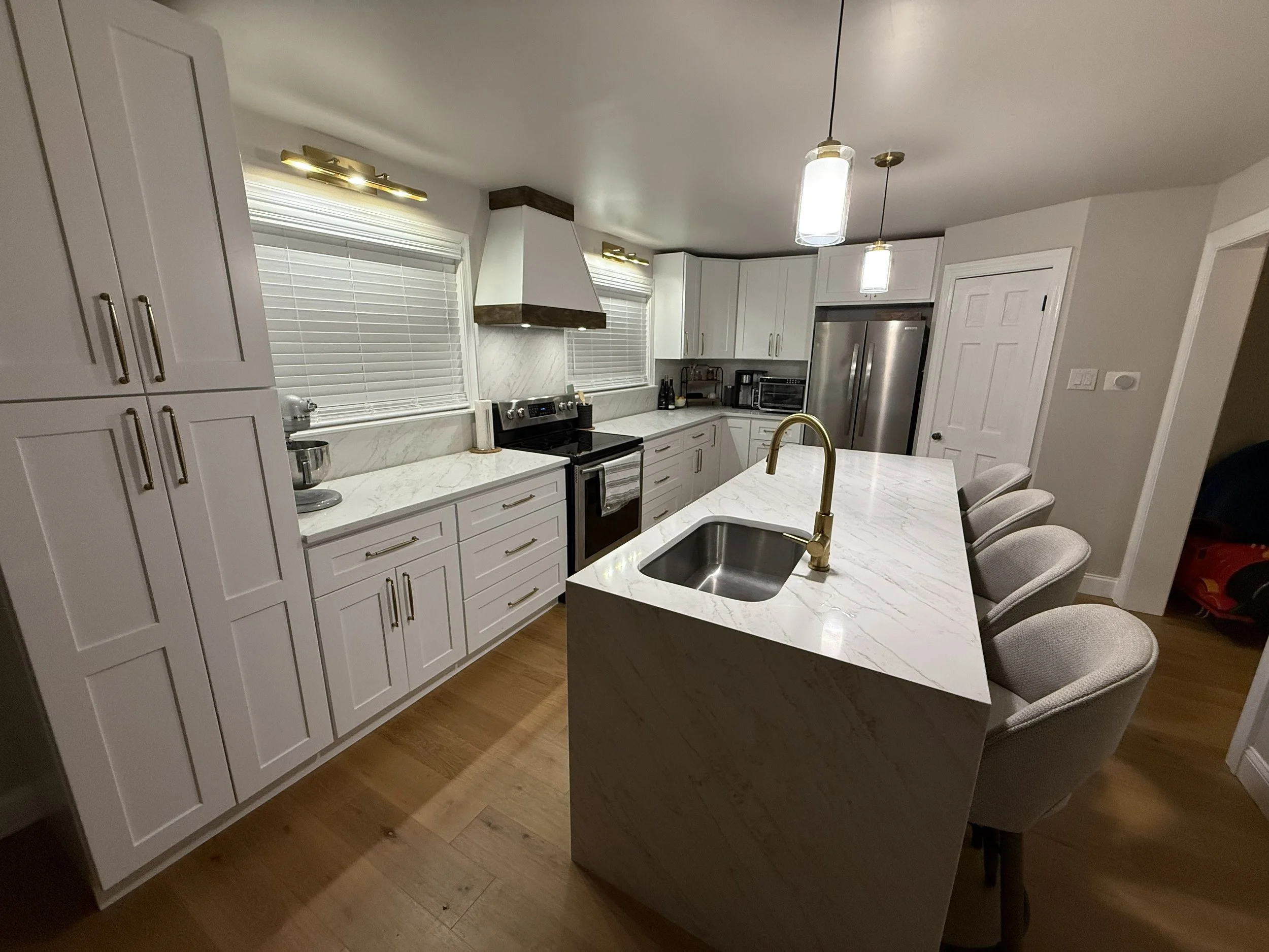 Modern white kitchen remodel with quartz countertops, large island seating, custom cabinetry, and stainless steel appliances in Bucks County Pennsylvania
