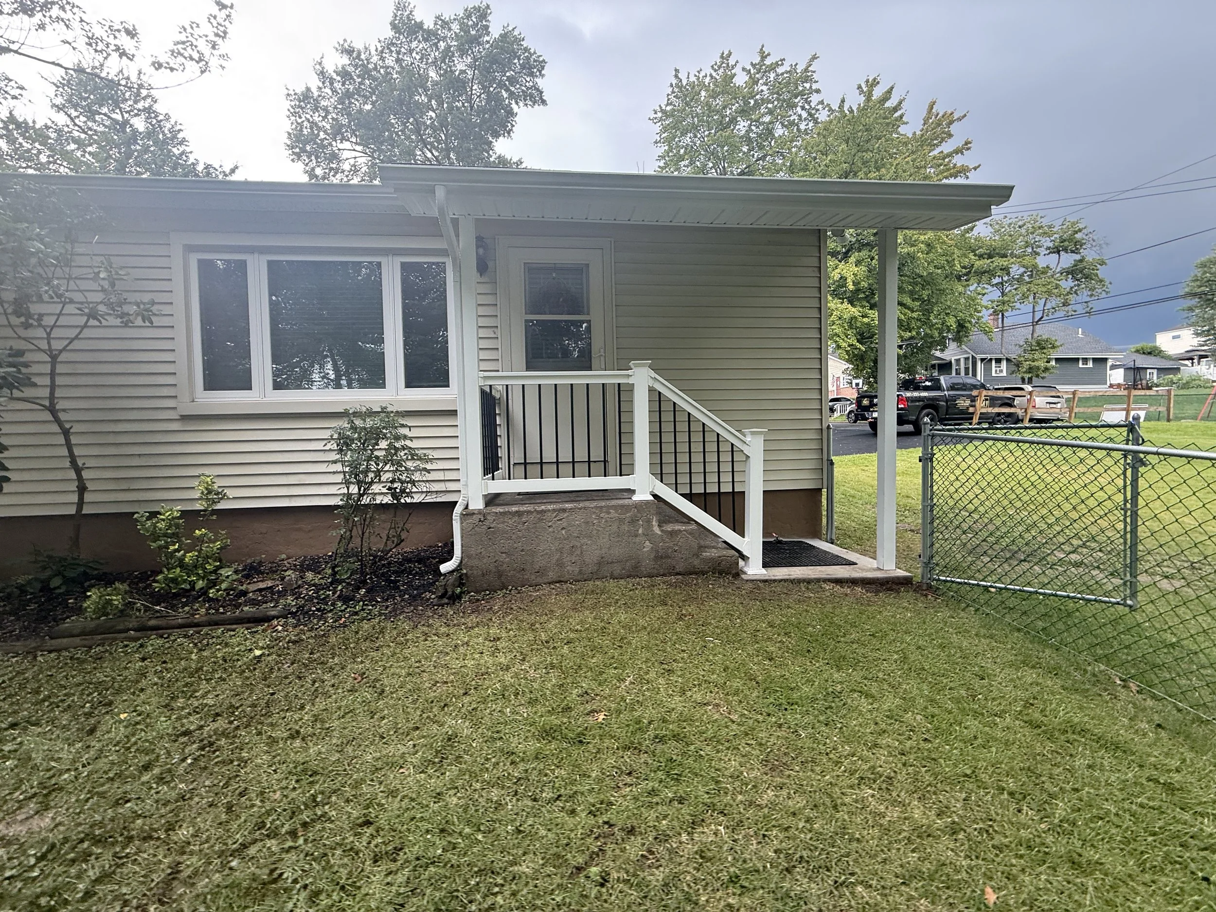 Single-story home with light siding, white railings, and a small covered front entry.