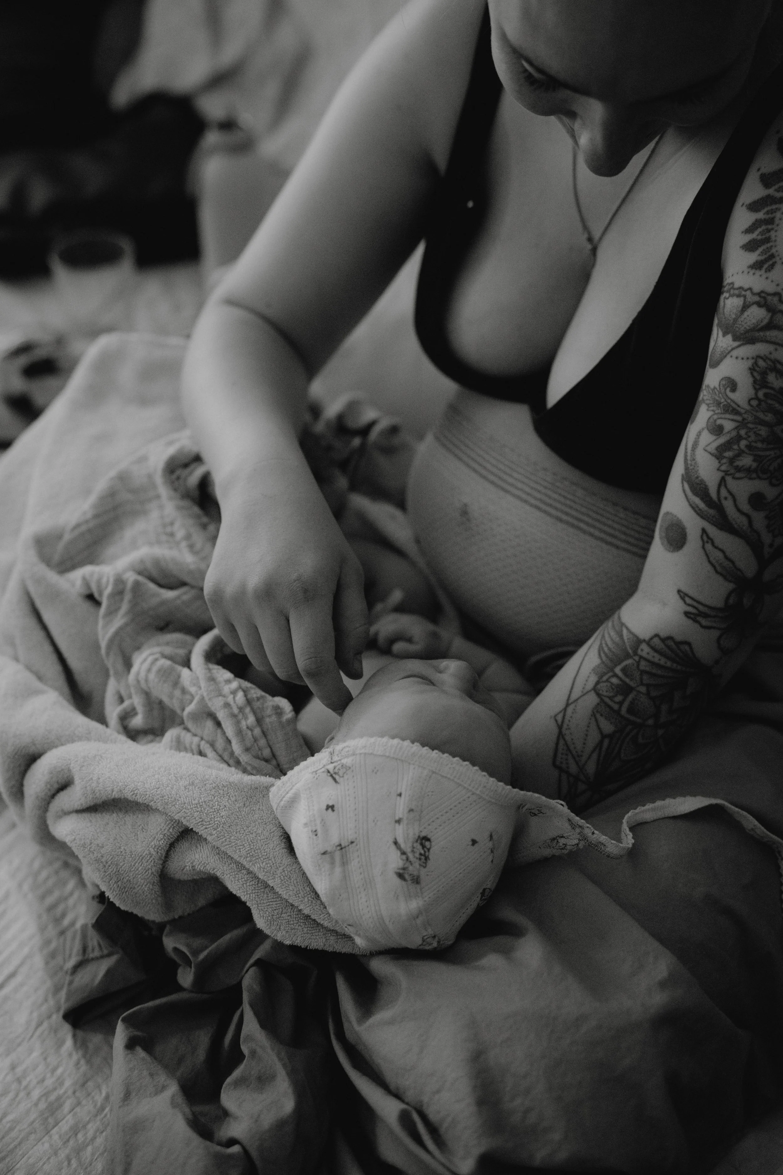 Eine Frau mit tätowierten Armen und einem Kinderwagen mit einem Baby.