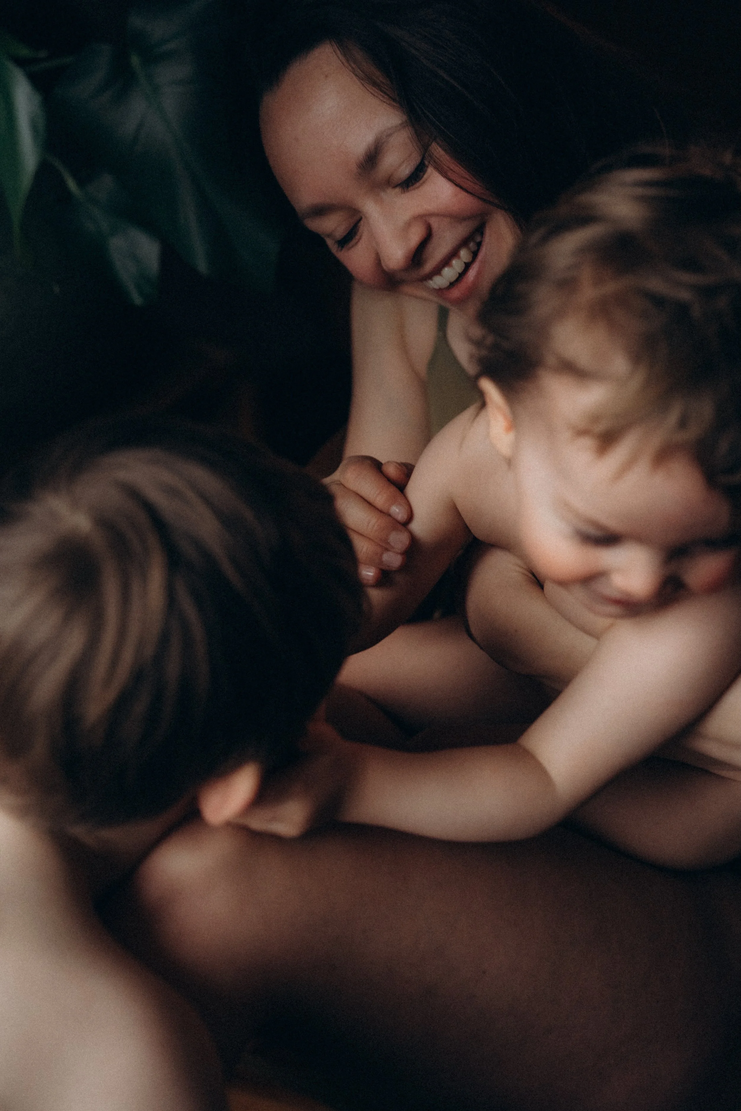 Eine glückliche Familie, bestehend aus einer Frau und zwei kleinen Kindern, die eng umarmt und lachen.