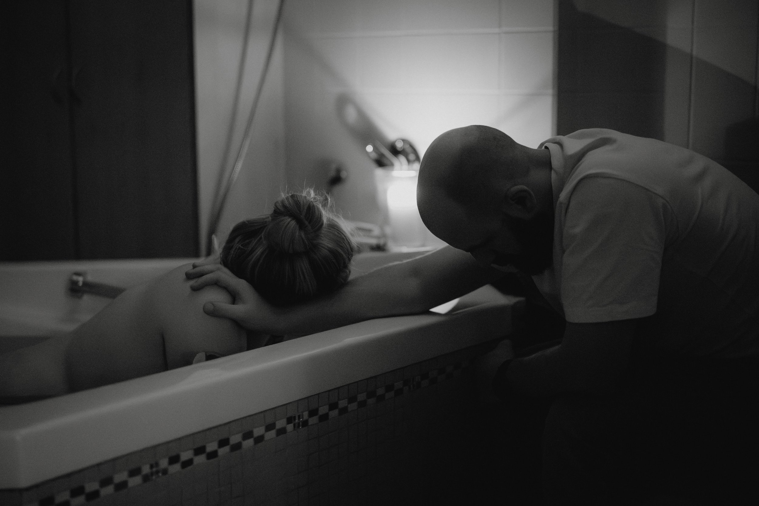 Ein Mensch liegt im Bad, während ein Pflegepersonal sie tröstet und ihnen über den Rücken streichelt.