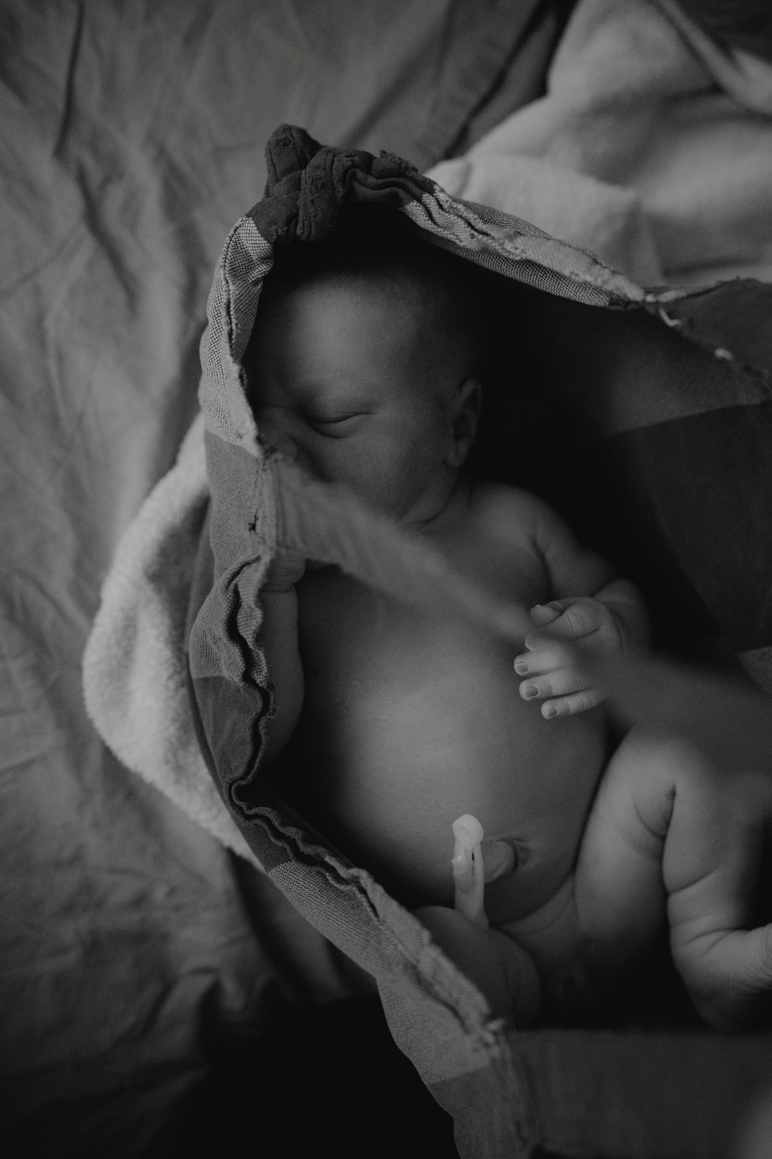 Ein neugeborenes Baby liegt in einem Handtuch oder Tuch und schläft.