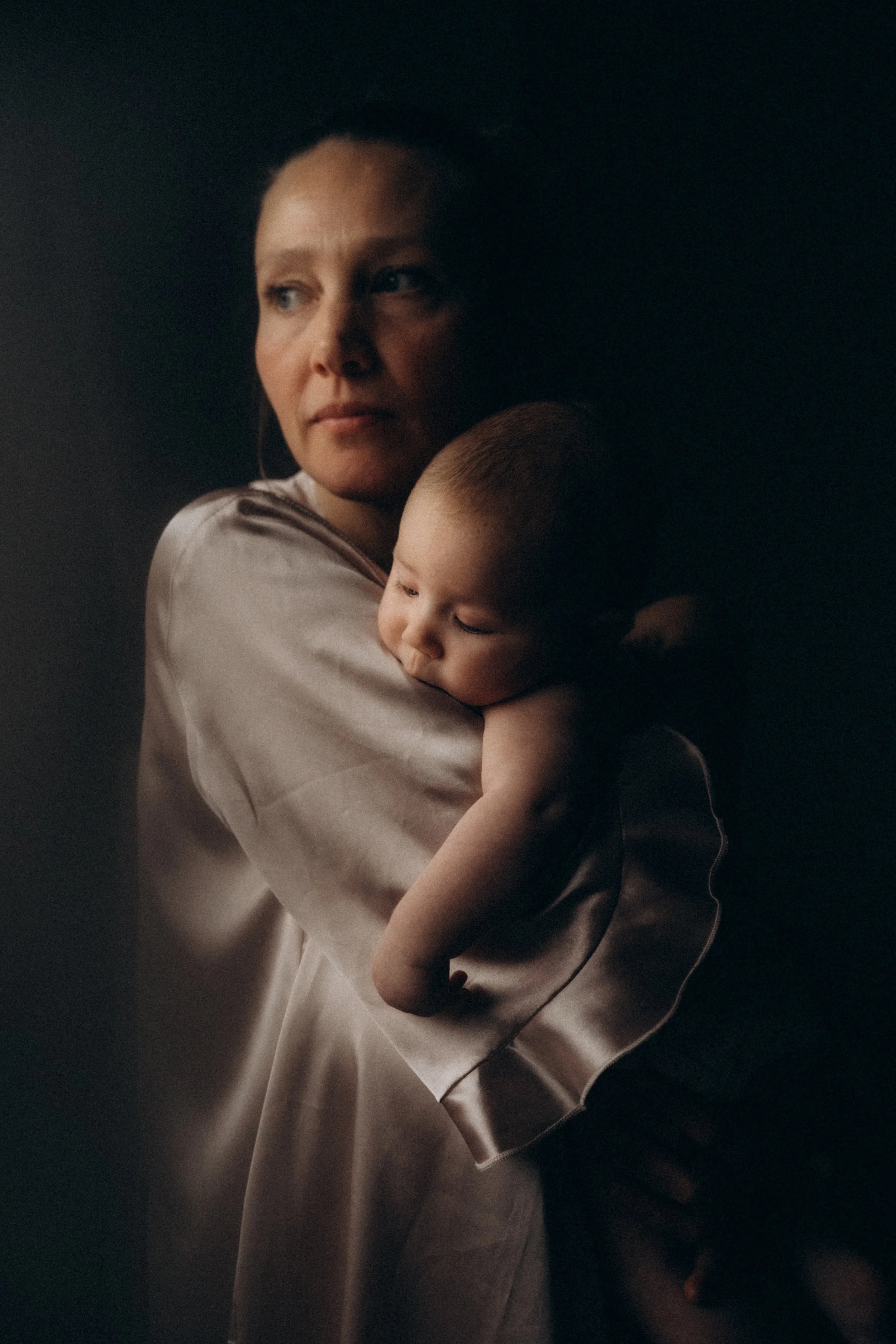 Eine Frau hält einen schlafenden kleinen Jungen in ihren Armen, beide sind in sanftes Licht gehüllt.