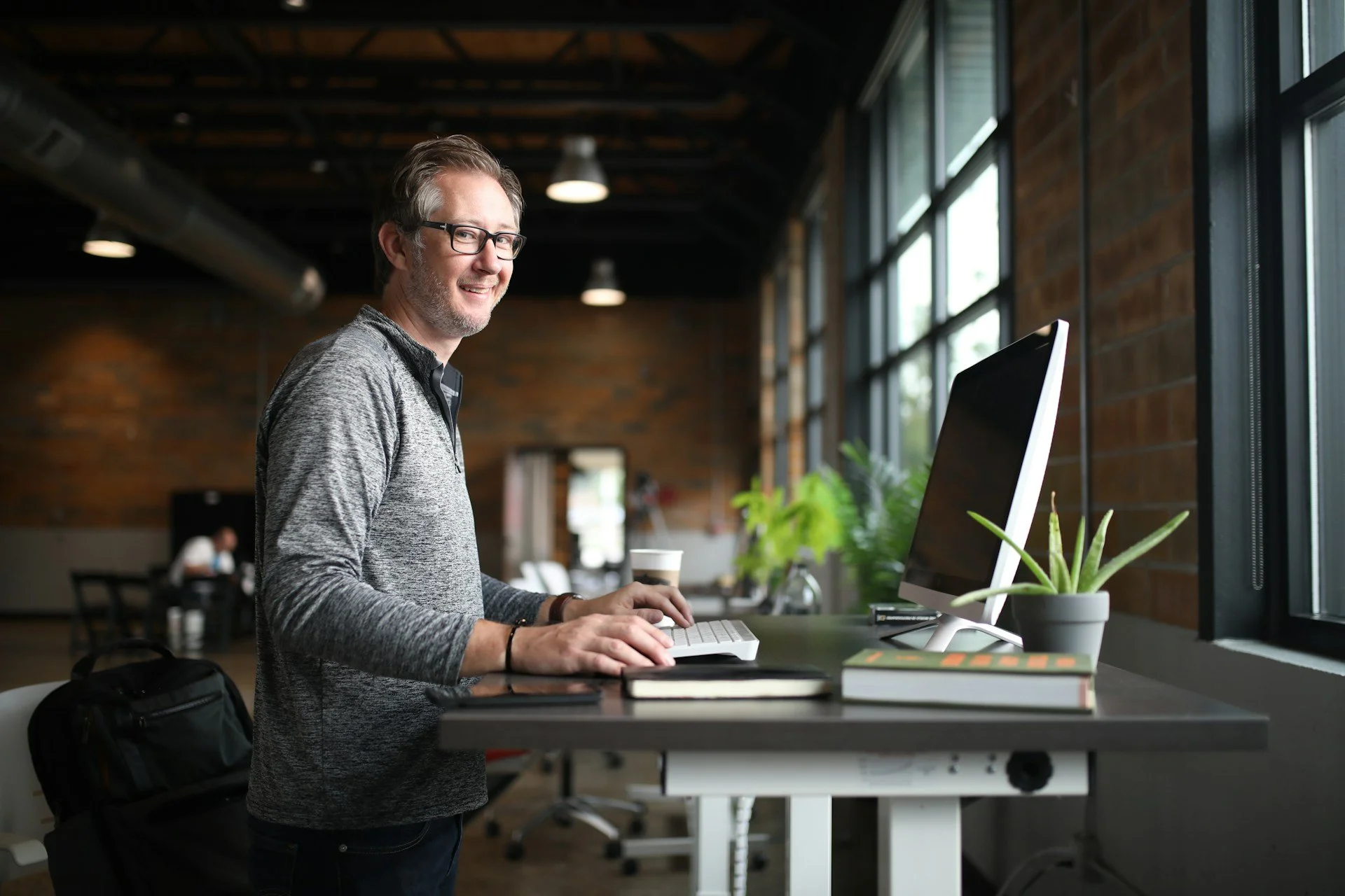 Man at standing desk smiling at camera