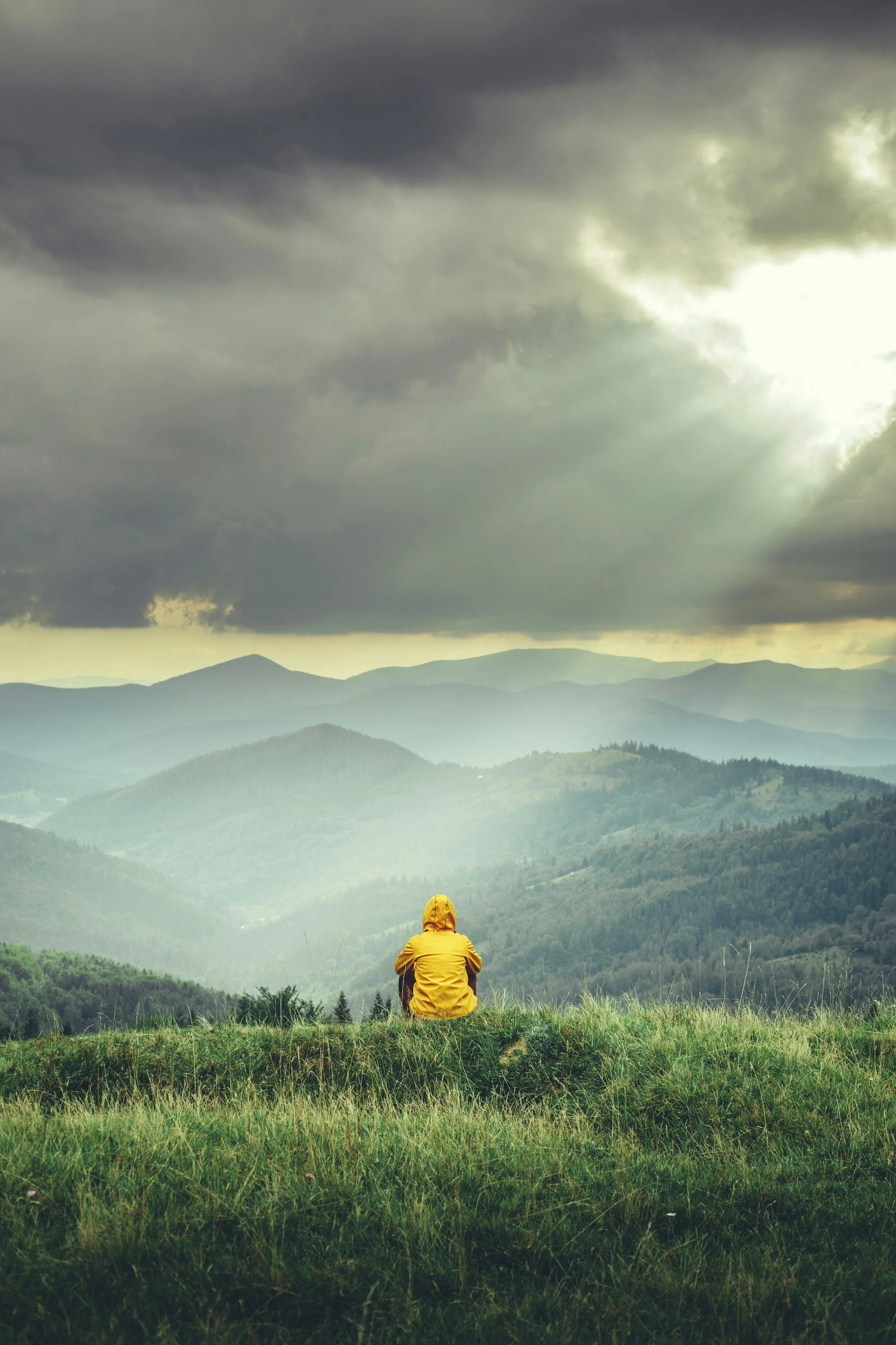 Person sitting on hilltop looking out