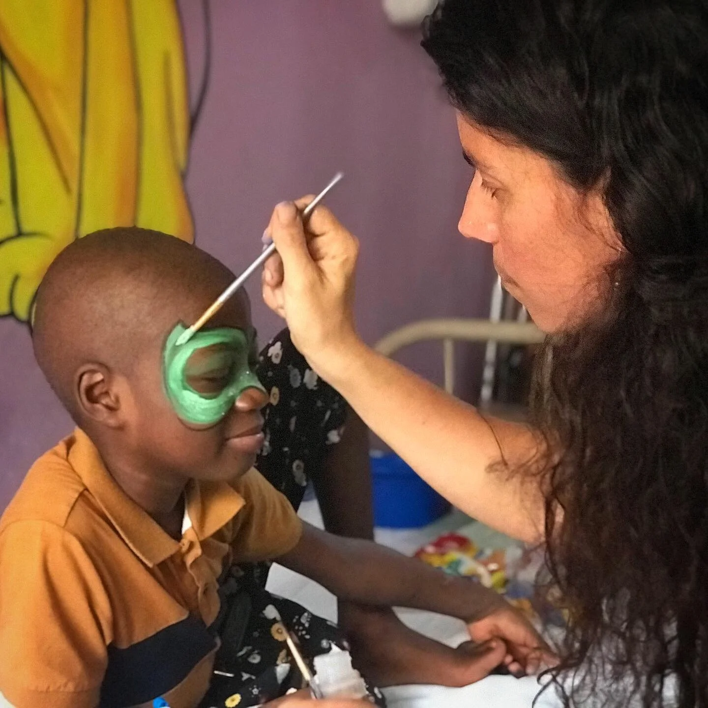 An artist paints a boy's face like a superhero mask 