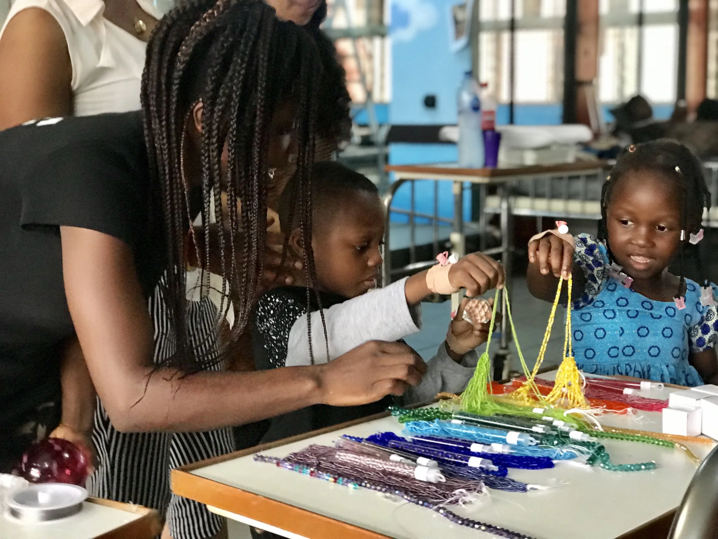 A woman helps children playing with colorful beads 