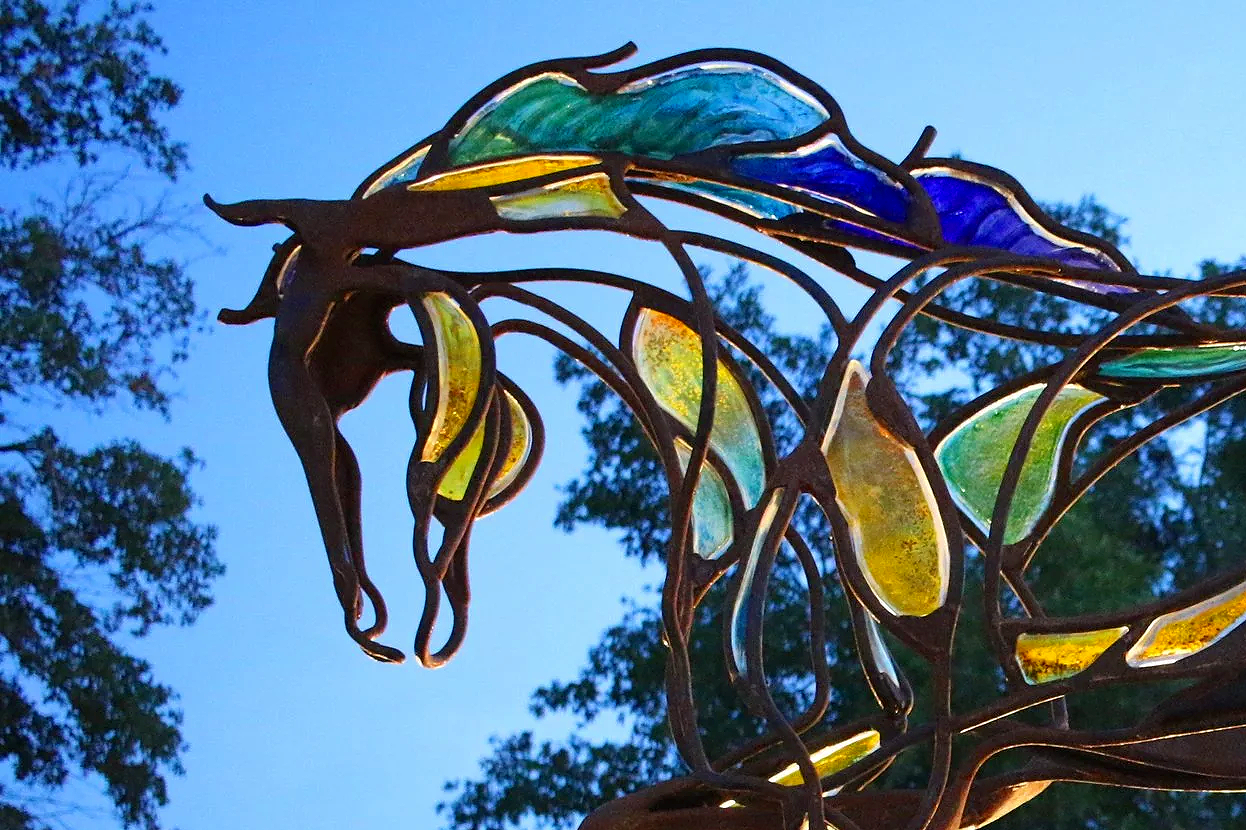 image of metal and glass horse sculpture with sky showing through negative space 