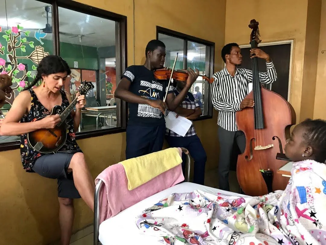 A group of musicians play for a girl in a hospital bed 