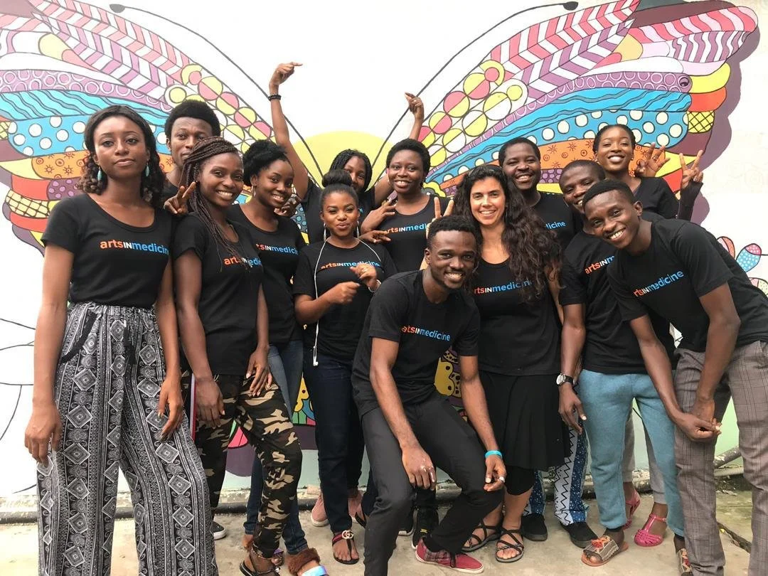 A group of artists in matching shirts smile for the camera 