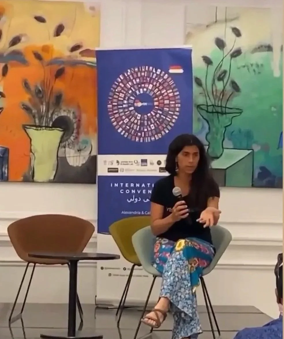 A woman delivers a lecture in front of colorful artwork