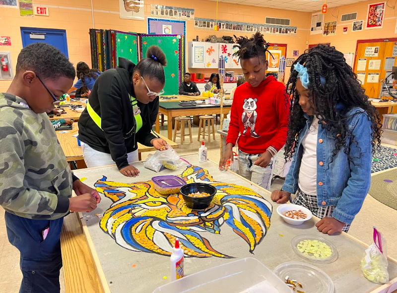 Children working together on a large mosaic of a wildcat