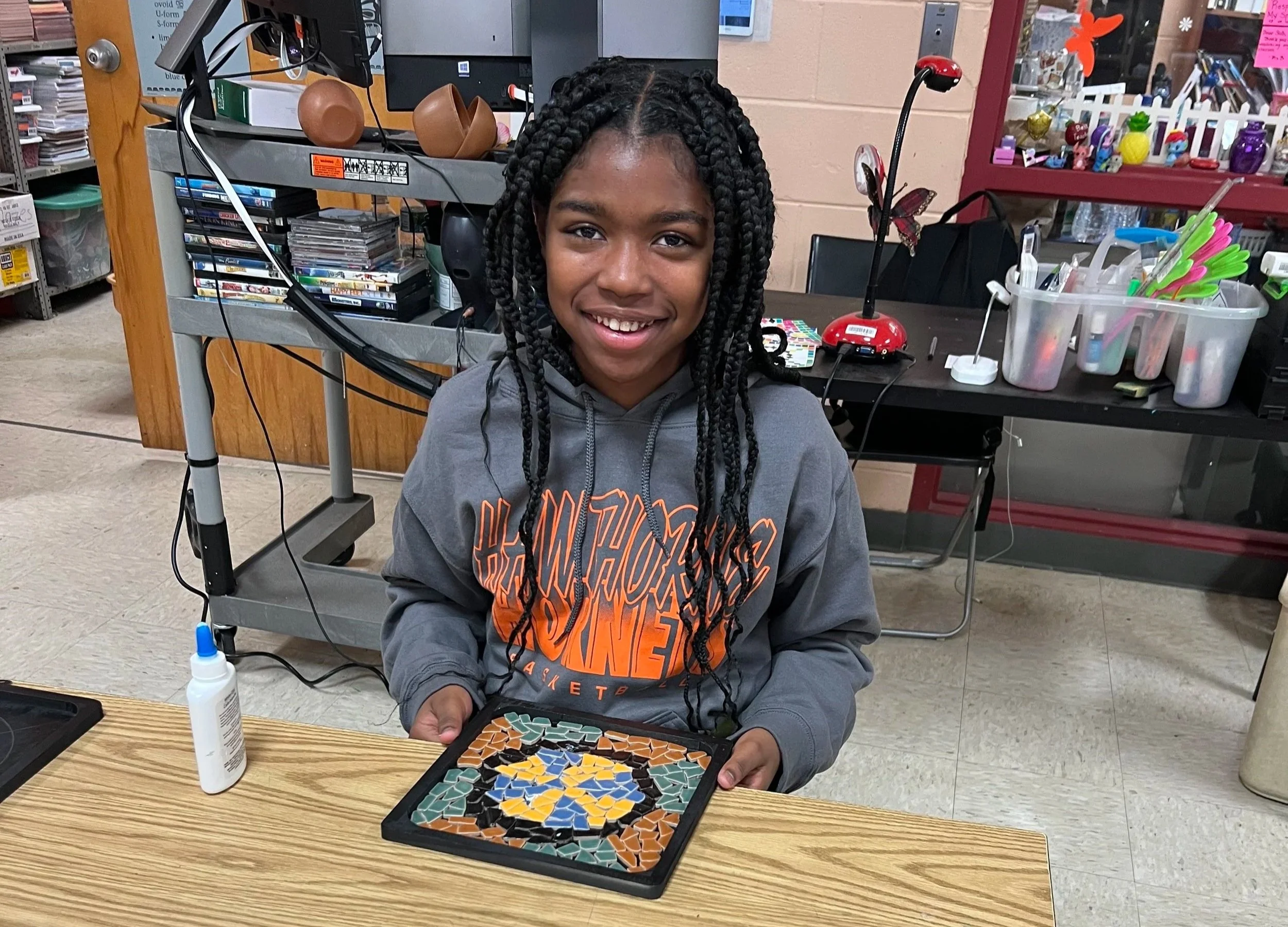 A proud student shows off her mosaic art 