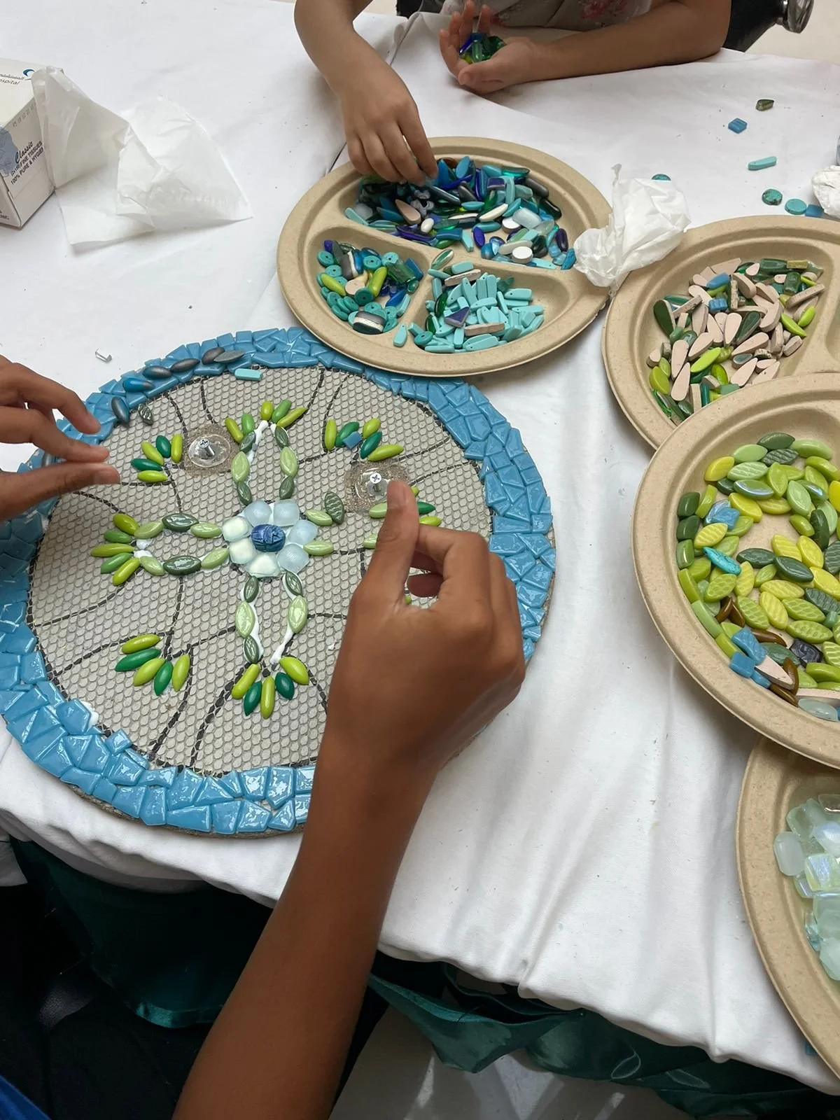 A close up image of hands creating a mosaic mandala 