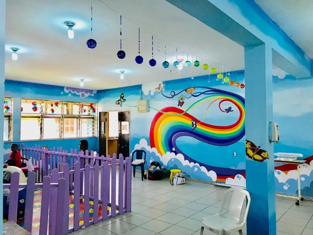 Image of a rainbow mural with glass balls strung in a line also in a rainbow 