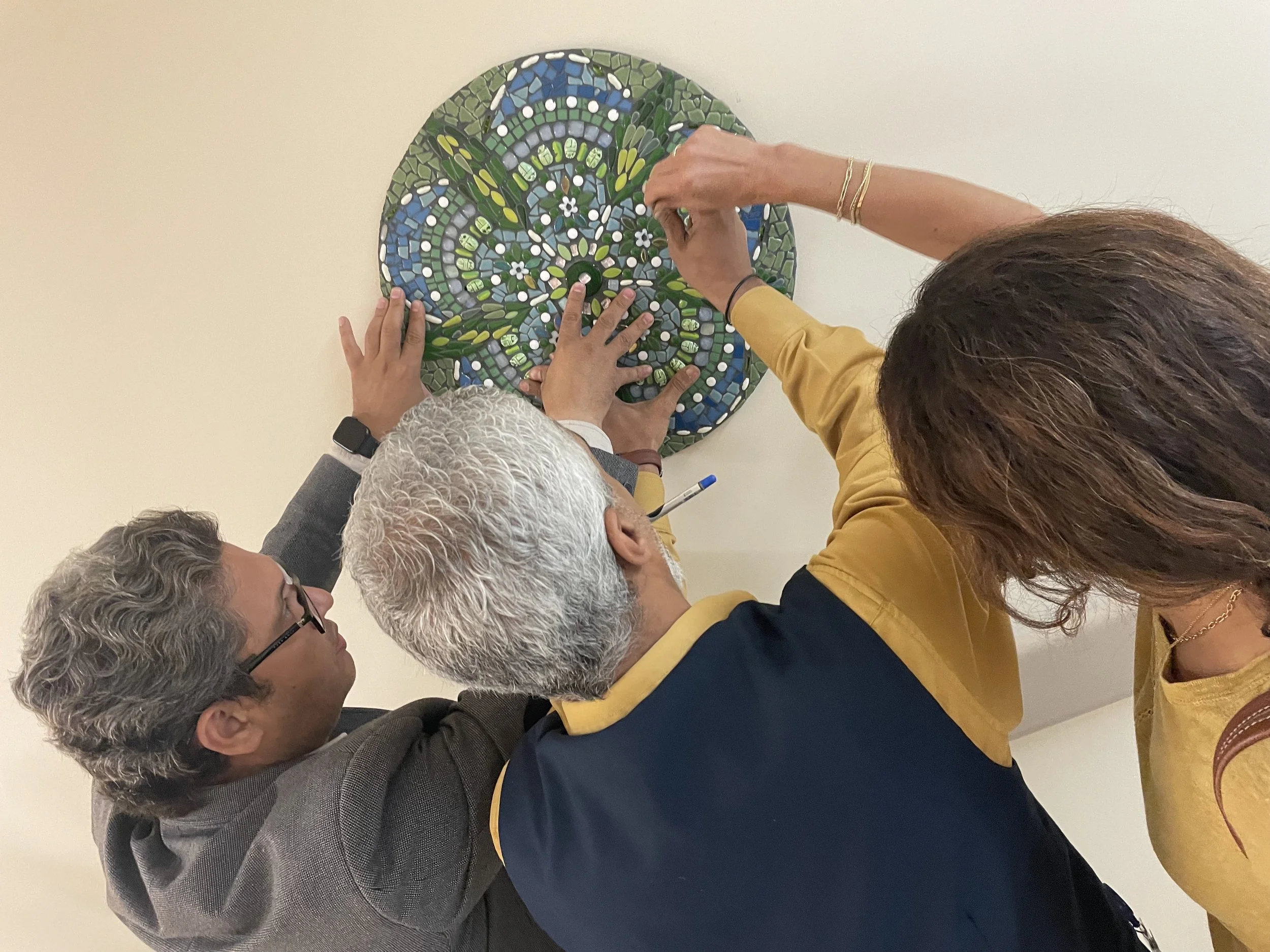 3 people work together to install a mosaic disc