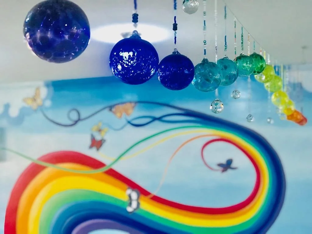 handblown glass orbs float in front of a rainbow mural 