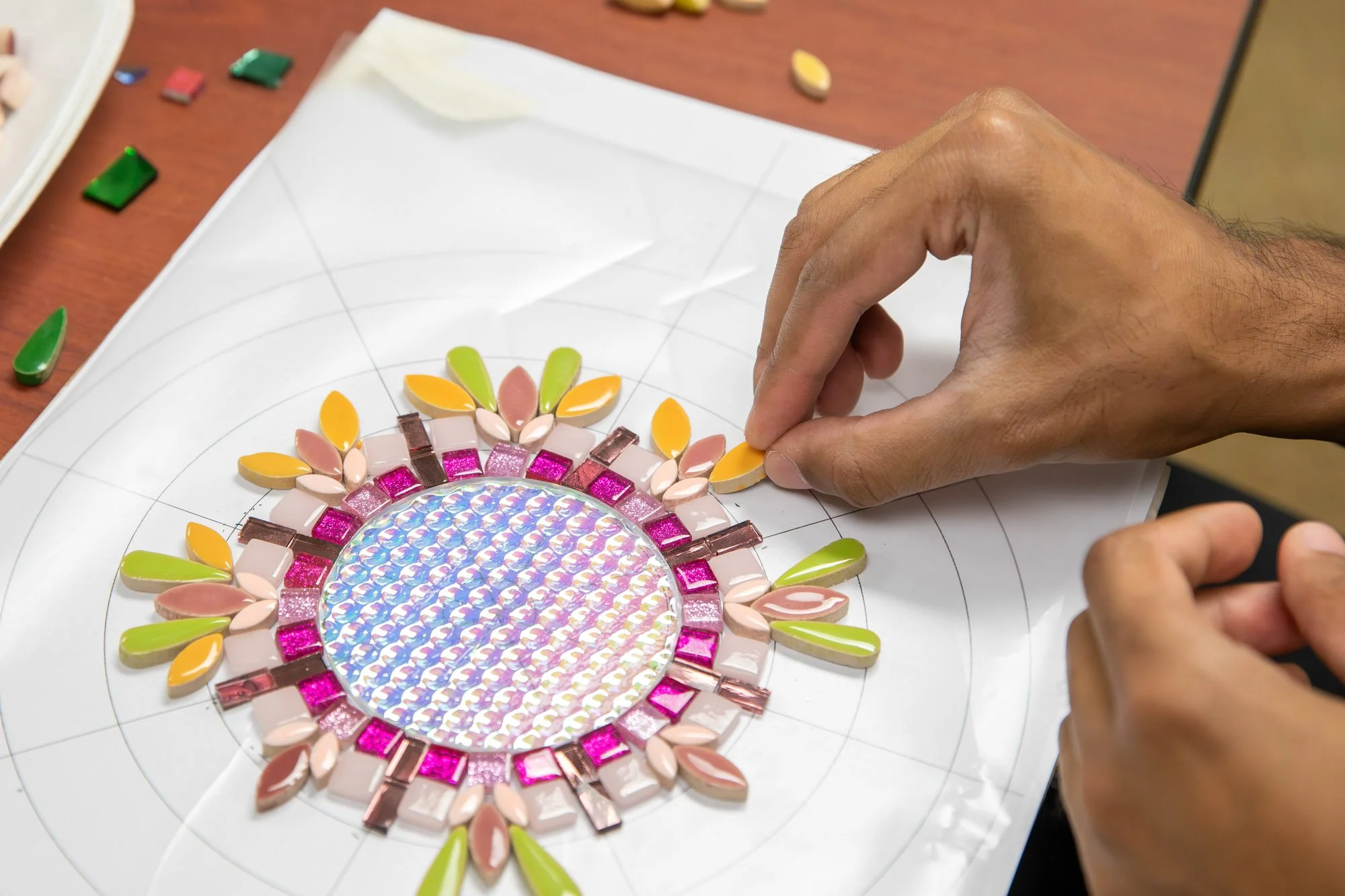 a hand creates a mosaic mandala 