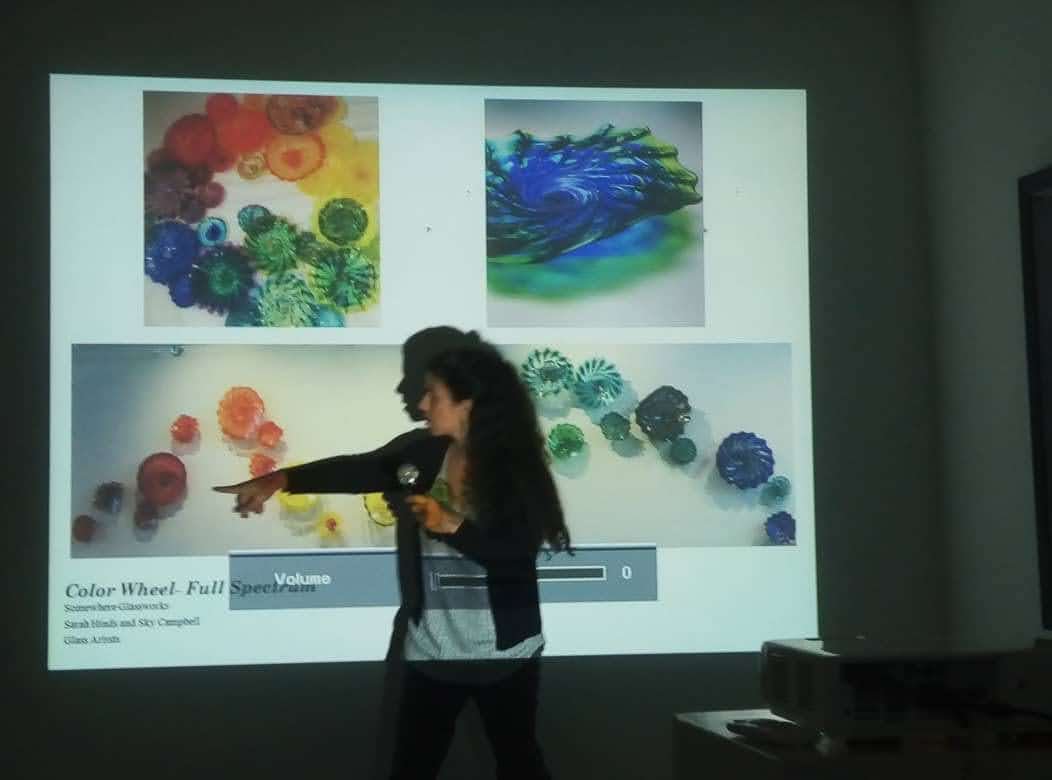 A woman presents a lecture about handblown glass