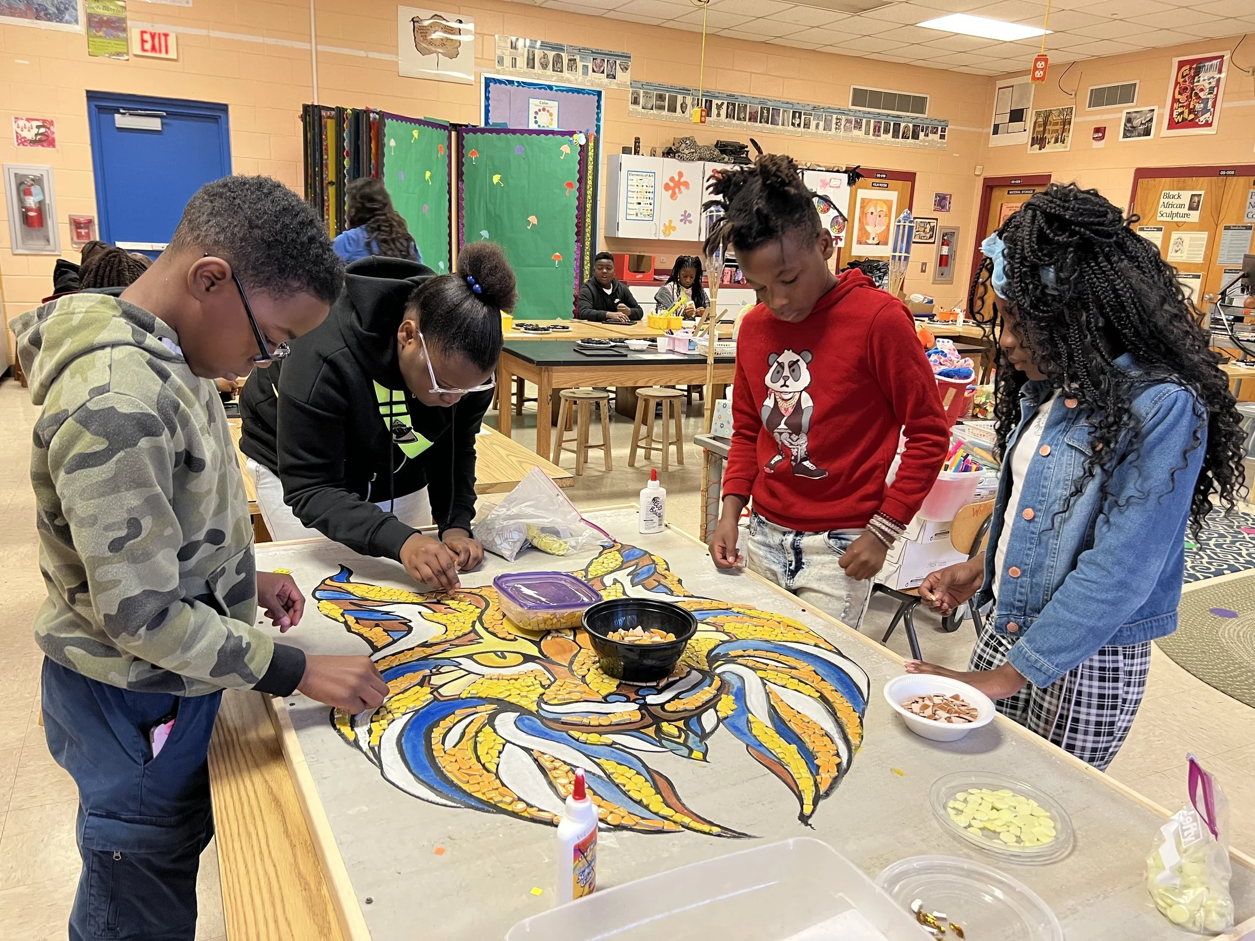 a group of students work on a mosaic mural 