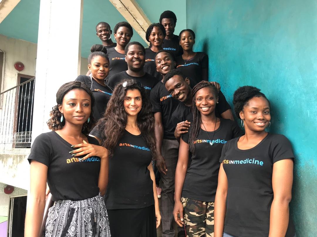 A group of artists in arts in medicine shirts smile happily 