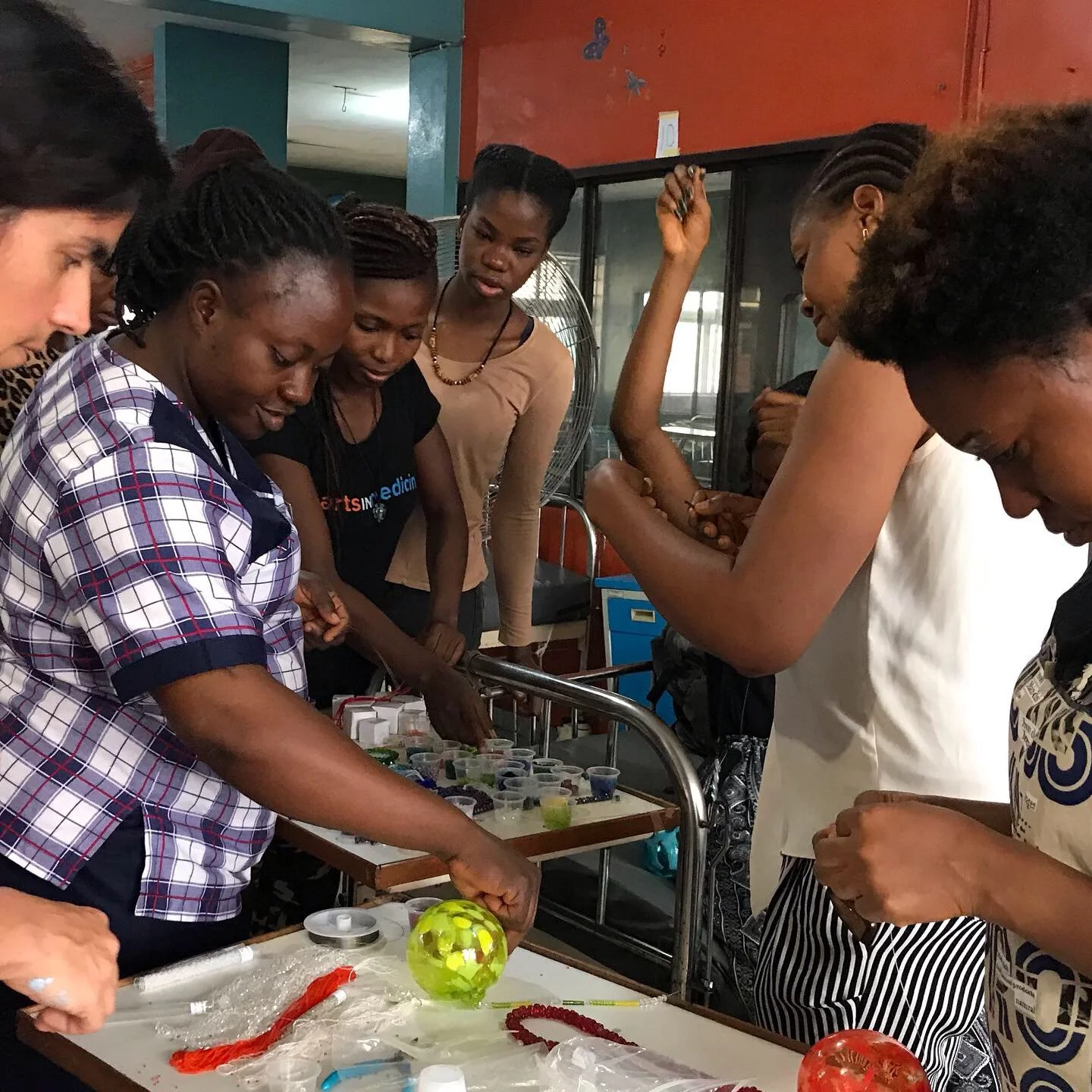 A group of women work together to string beaded prisms 