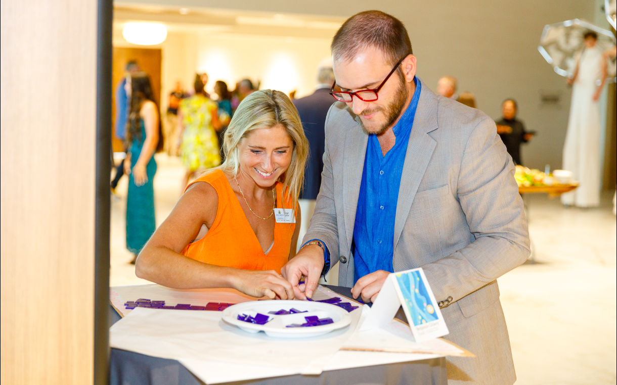 a couple works on a mosaic at a formal fundraiser