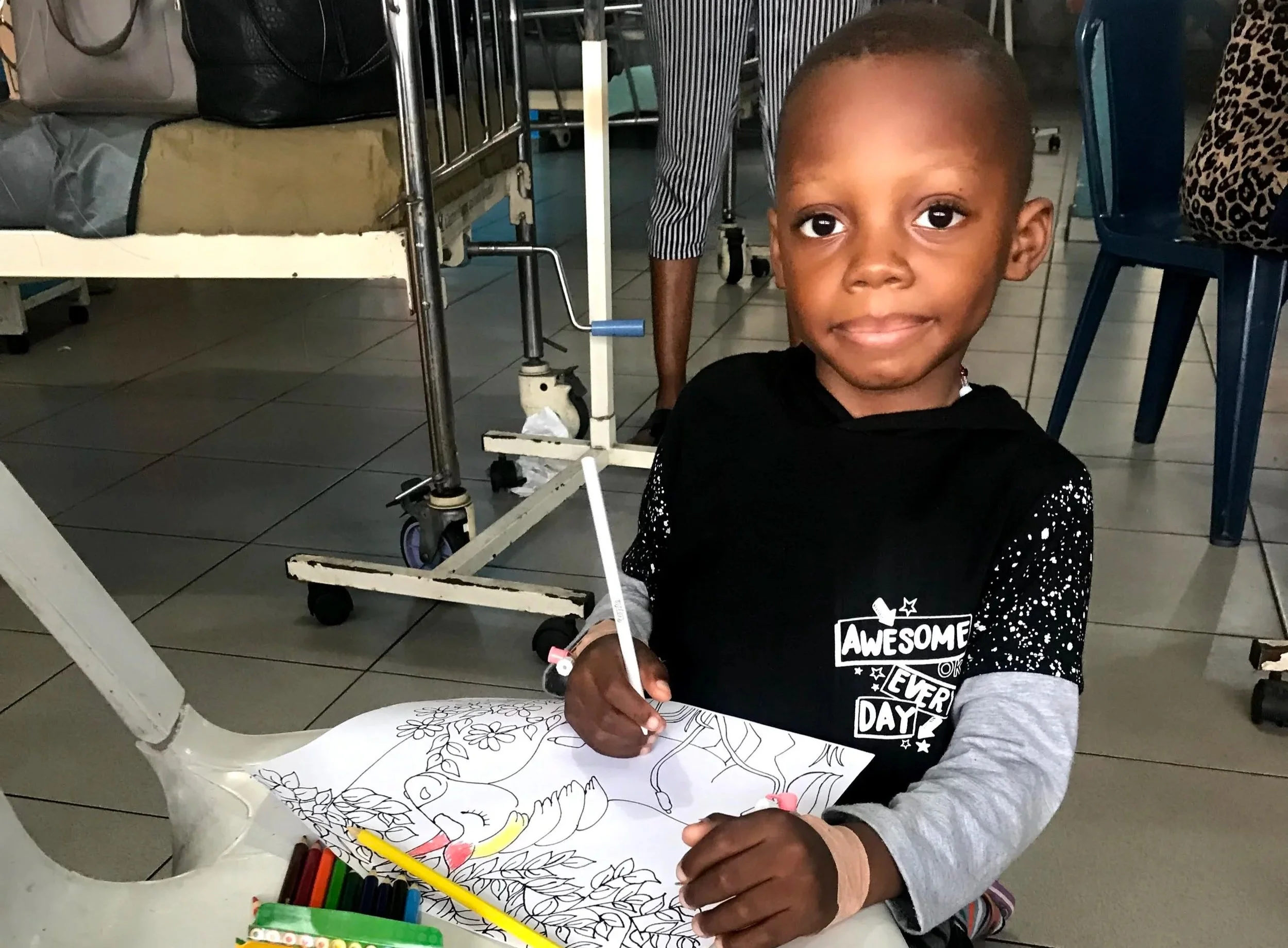 A little boy colors a picture on a plastic chair 