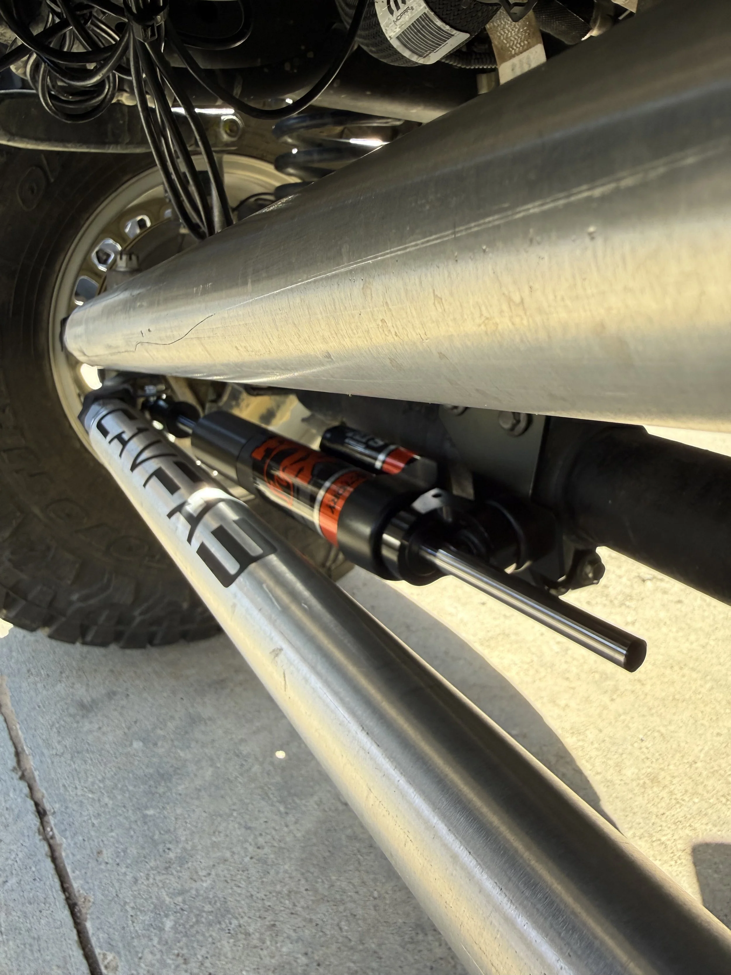 Close-up of a motorcycle's rear suspension and exhaust, showing a shock absorber and a chrome exhaust pipe.
