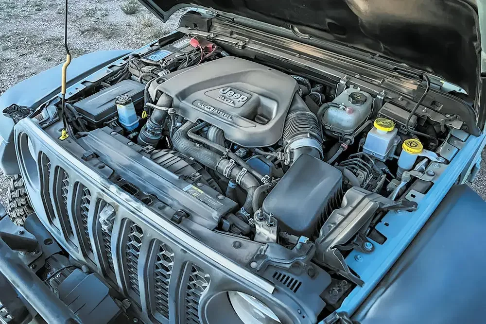 Under the open hood of a Jeep vehicle, showing the engine with a plastic cover labeled 'Jeep 3.6L V6'.