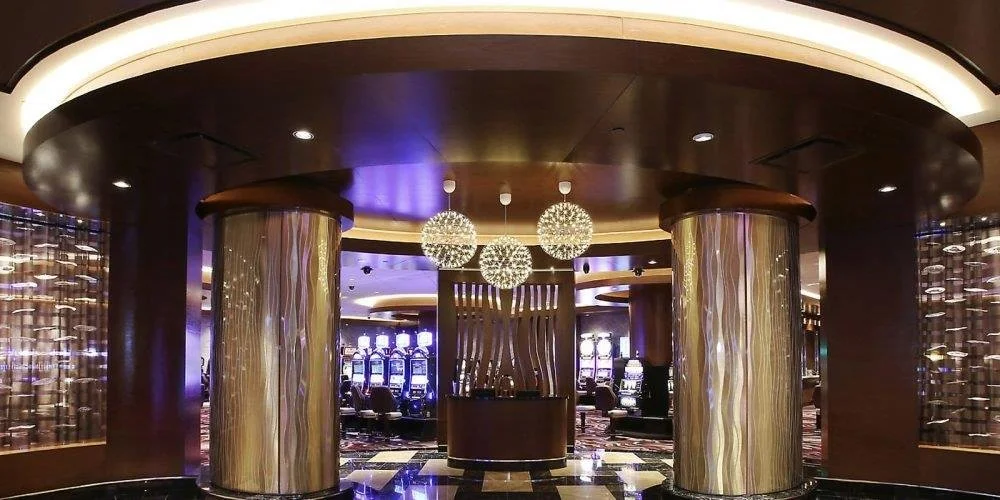 Interior of a luxurious casino, featuring a circular reception or service desk with decorative lighting and large, shiny columns
