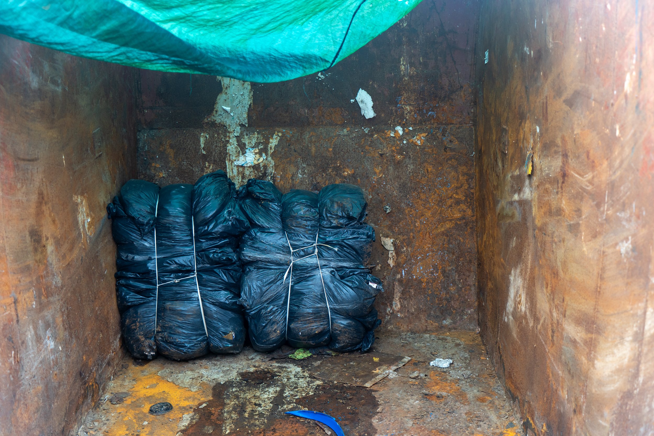 Two compacted black bags in a skip