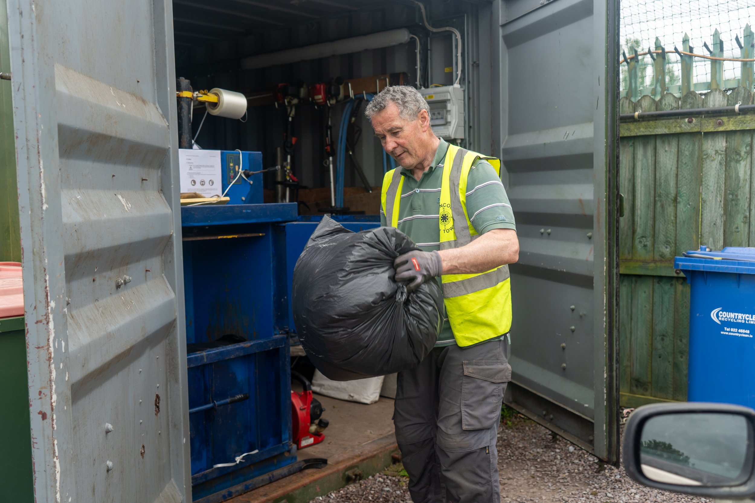 Person with black bag next to a compacting machine