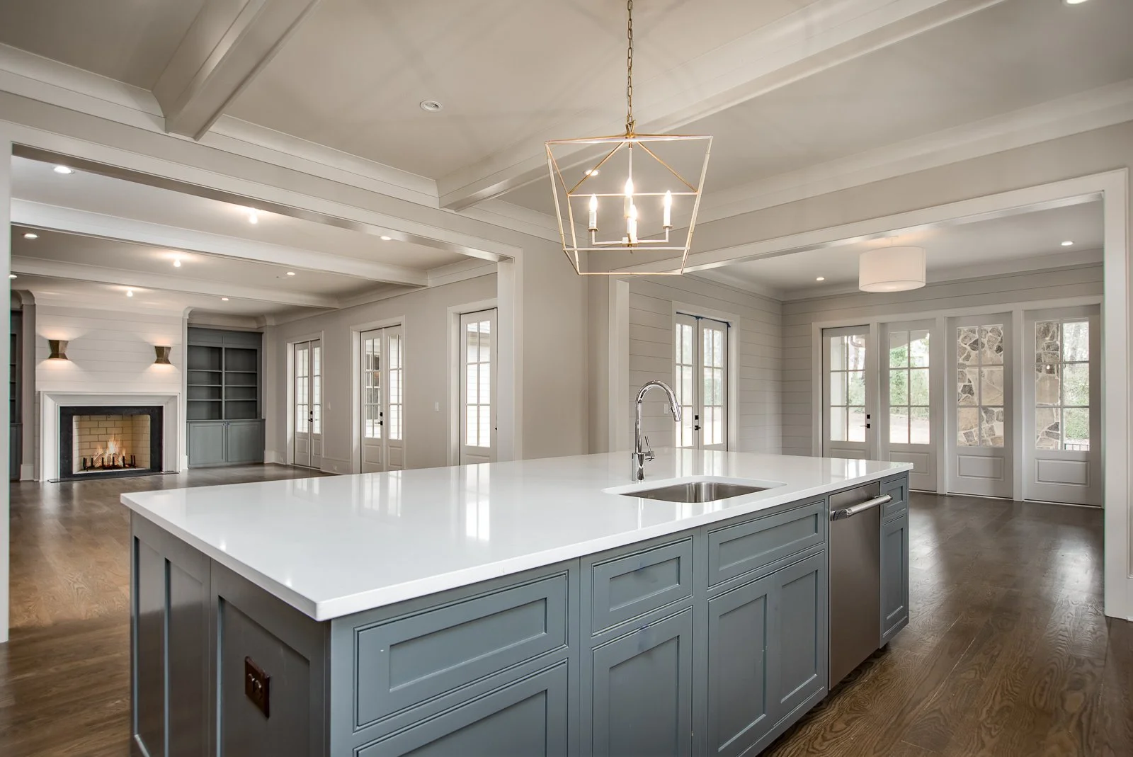 Modern kitchen with white island, blue cabinetry, hardwood floors, and large windows