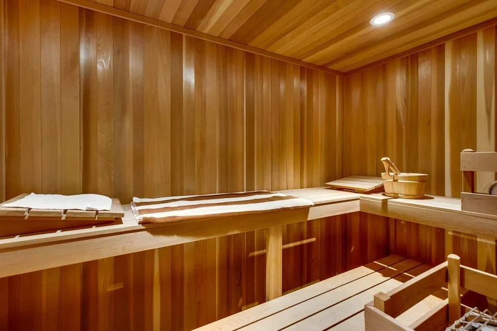 Interior of a traditional sauna room with wooden walls, benches, and a bucket with a ladle.