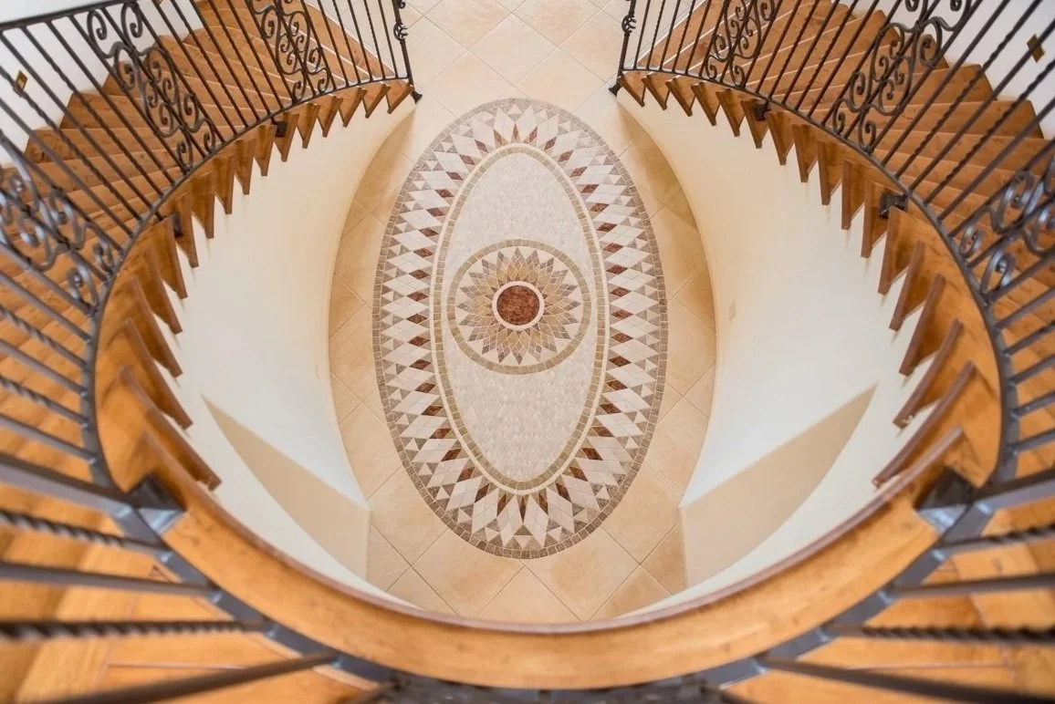 Intricate stairwell with wrought iron railing and mosaic inlaid floor.