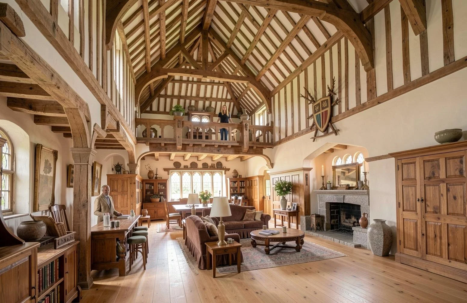 Spacious living room with wooden beams, furniture, and a fireplace, featuring a double-height ceiling, large windows, and a balcony above.
