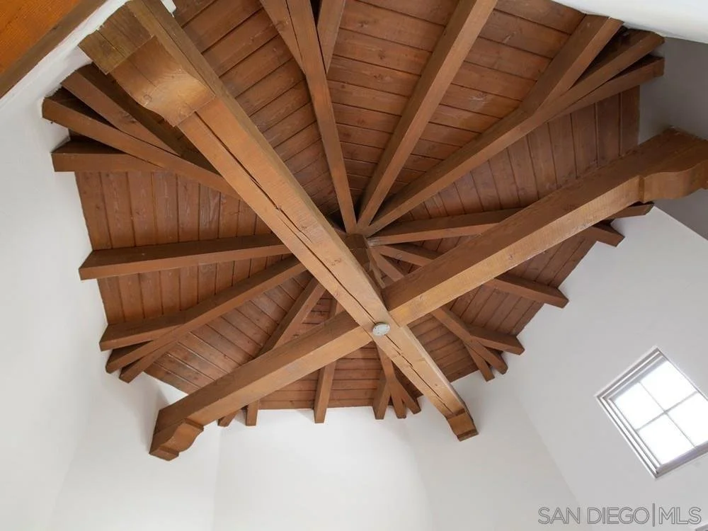 Wooden ceiling with a spiral beam design and a small window in the corner.