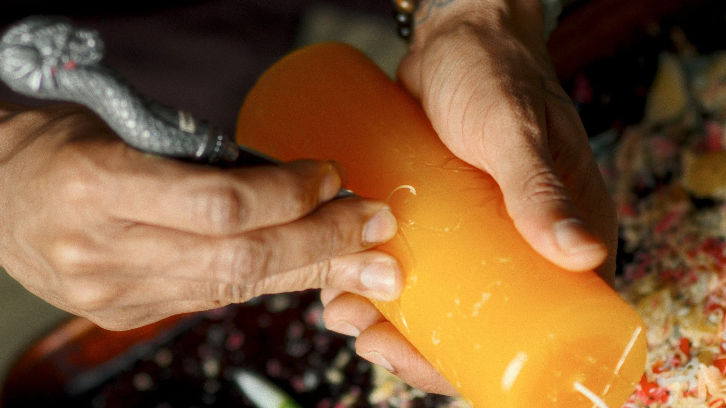 Close-up of hands carving a yellow  magical intention base candle.