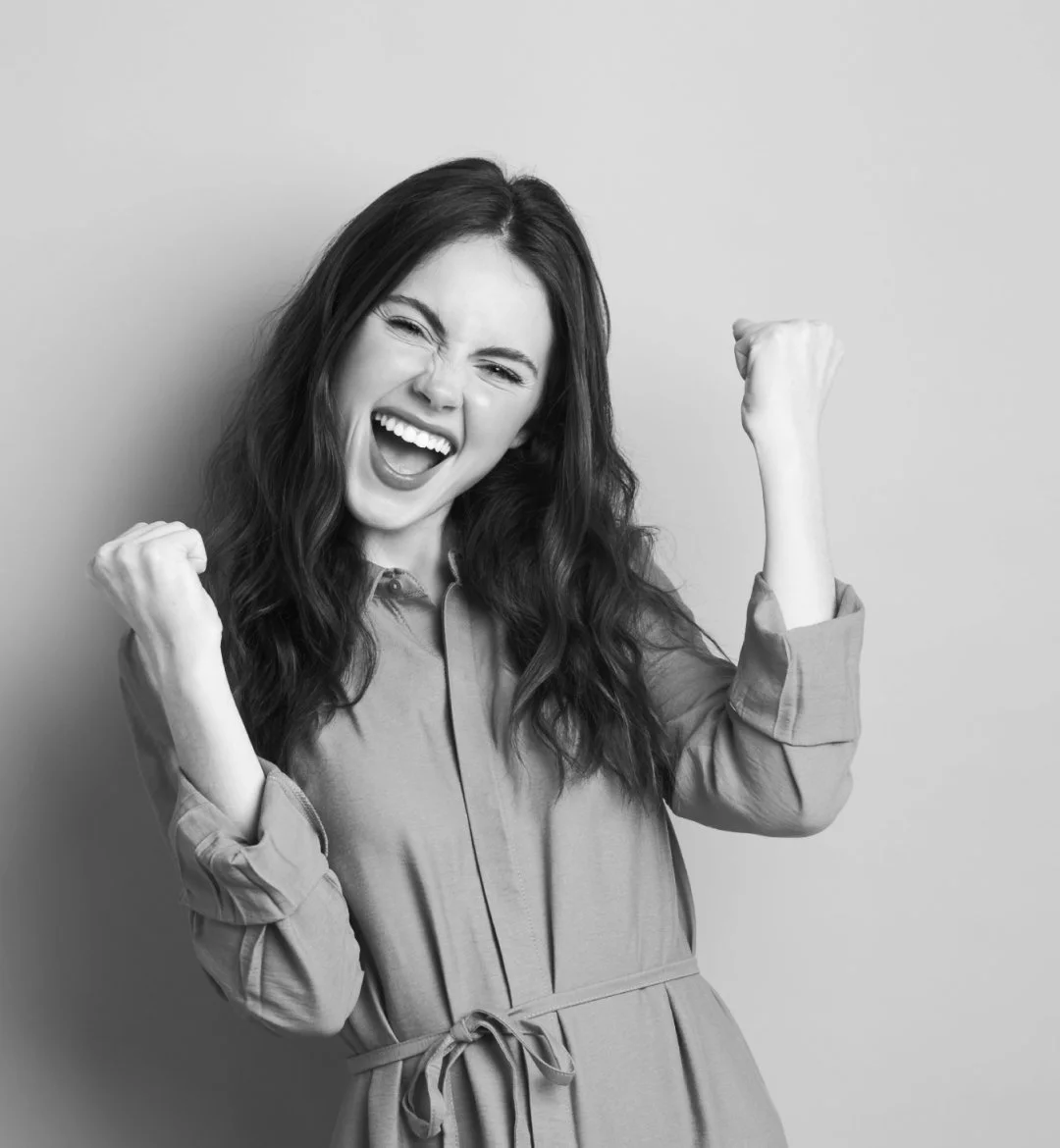 Woman celebrating with both fists raised looking happy, confident and triumphant, like she's just had great success doing something